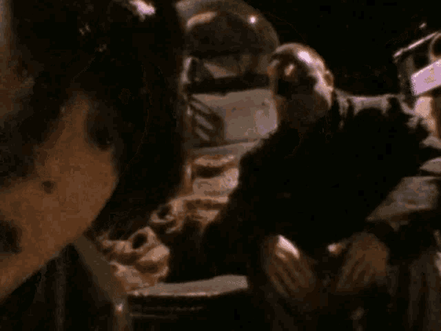 a group of people are sitting in a dark room and one of them is holding another man 's hand .