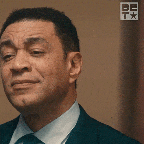 a man in a suit and tie is smiling with a be t logo in the background