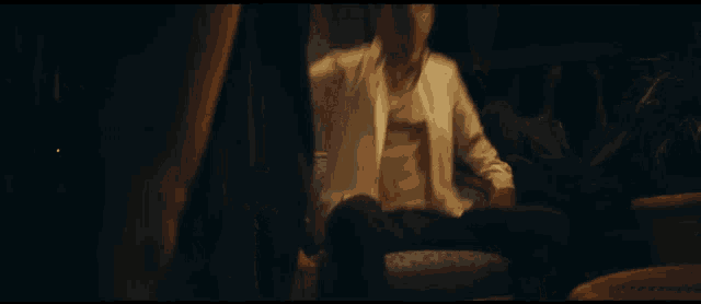 a man in a white shirt sits in a chair with his legs crossed