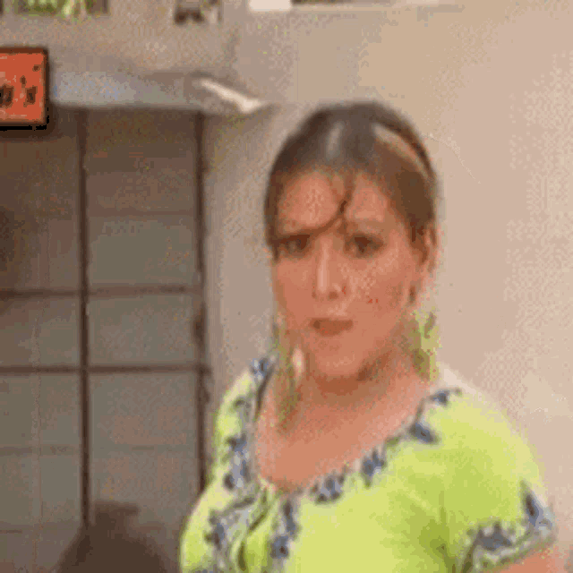 a woman in a green shirt is standing in front of a television .
