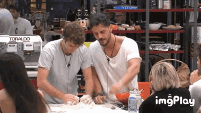 two men are kneading dough in front of a machine that says toraldo