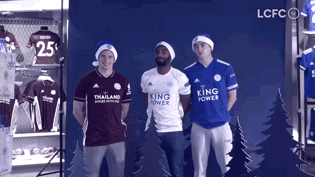 three men wearing shirts that say king power stand in front of a blue background