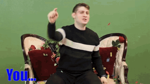 a man in a black and white sweater is sitting on a couch with the word you above him