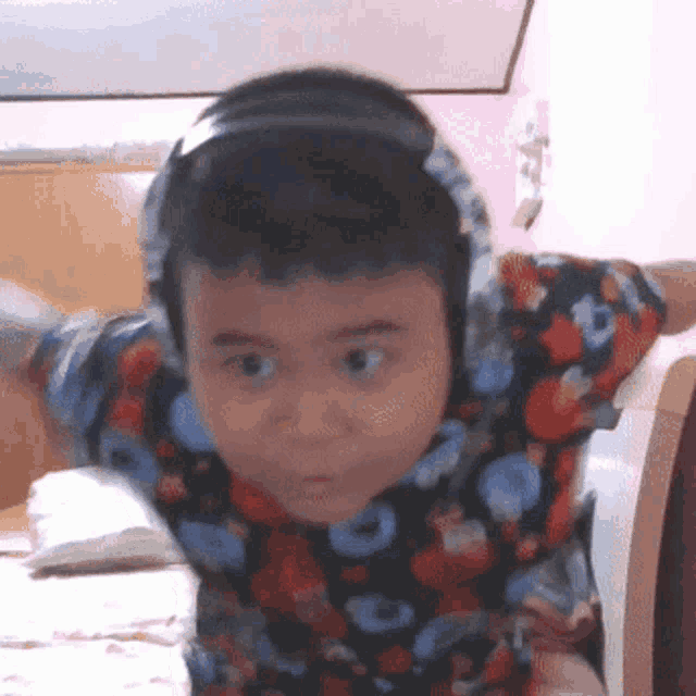 a young boy wearing a hoodie and headphones looks at the camera with his arms outstretched