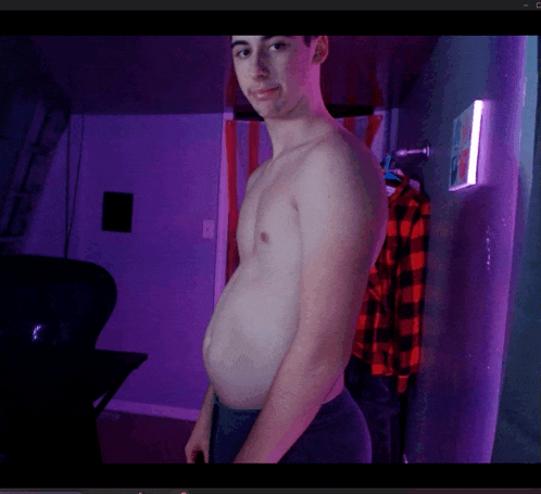 a shirtless man is standing in a room with purple lights