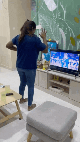 a woman is standing in front of a television in a living room while dancing .