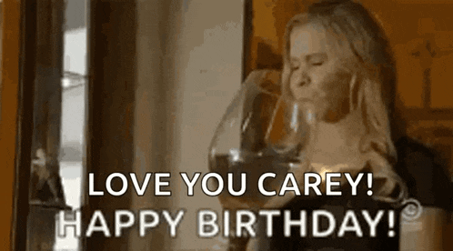a woman is drinking a glass of wine and saying `` happy birthday '' .