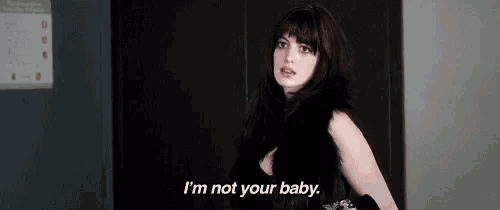 a woman in a black dress is standing in an elevator and saying `` i 'm not your baby . ''