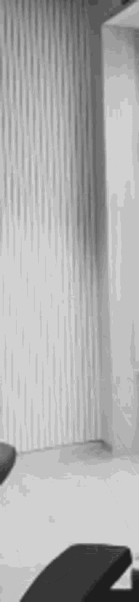 a black and white photo of a chair in a room with a white wall behind it .
