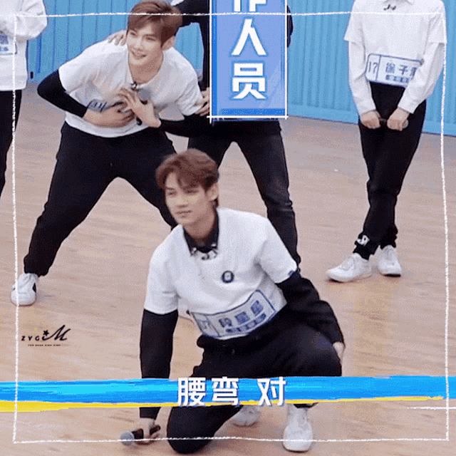 a group of young men are kneeling on the floor with a sign that says ' a ' on it