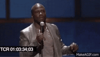 a man in a suit is standing in front of a microphone and talking into it .