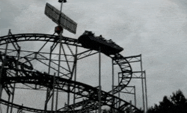 a roller coaster is going around a curve with a cloudy sky behind it