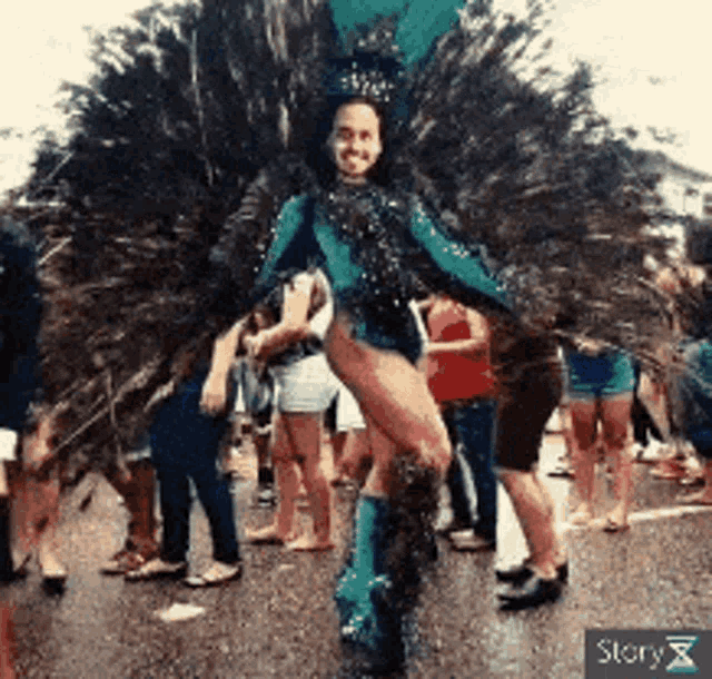 a woman in a peacock costume is dancing in front of a crowd