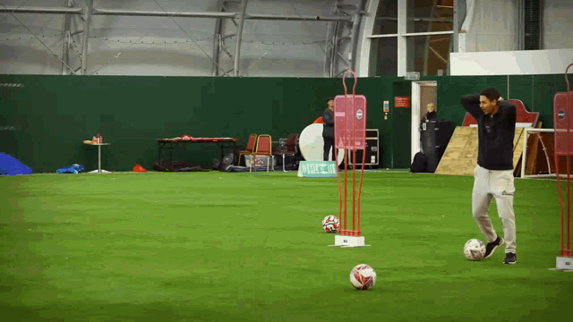 a man is kicking a soccer ball in a gym with a sign that says ' indoor stadium ' on it