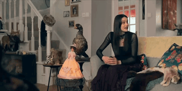 a woman is sitting on a couch in front of a stuffed animal