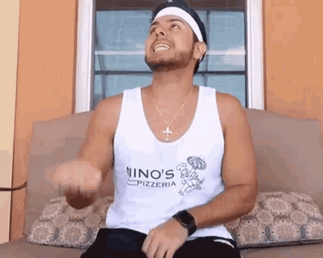 a man wearing a white tank top that says nino 's pizzeria on it