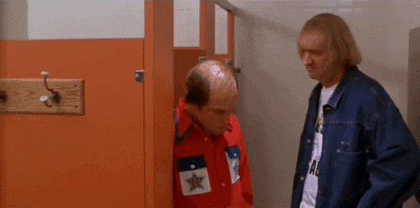 two bald men are standing in a public restroom .