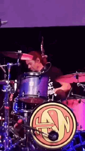 a man is playing drums in front of a drum set with the letter n on it