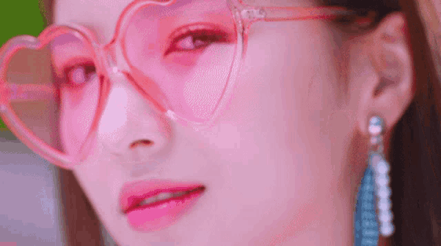 a close up of a woman wearing heart shaped sunglasses .