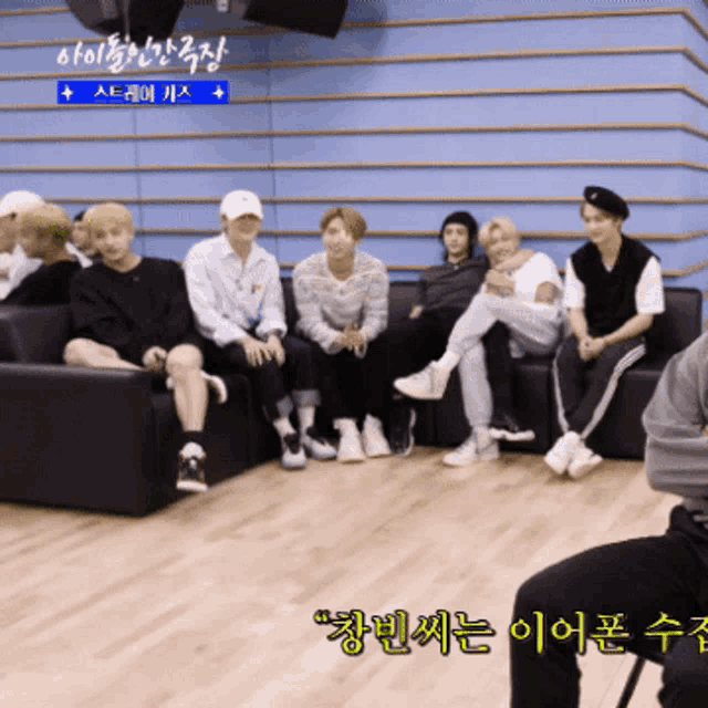 a group of people sitting on a couch with a blue wall behind them that says ' a ' on it