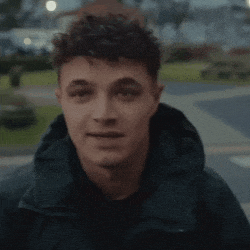 a man wearing a black jacket with a hood looks at the camera