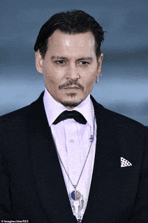 a man in a tuxedo with a bow tie and a necklace