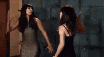 two women are standing next to each other in a room holding hands .