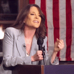 a woman stands at a podium holding a microphone
