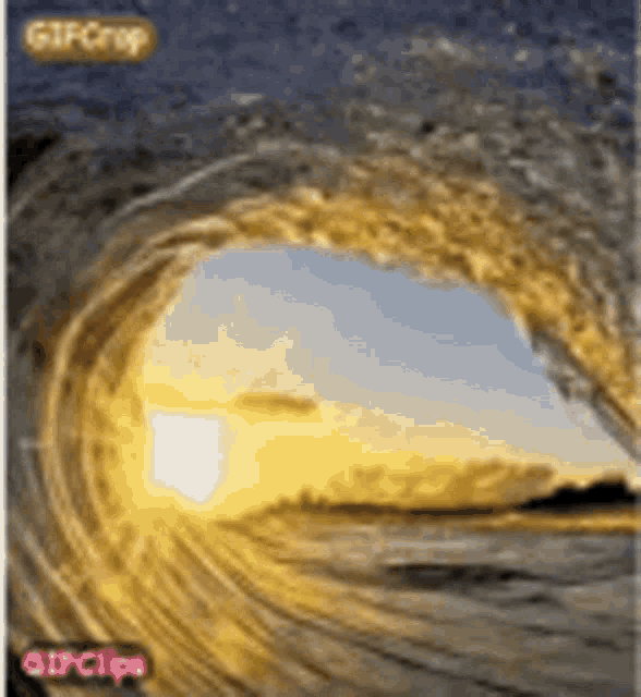 a gif of a wave breaking on a beach at sunset .