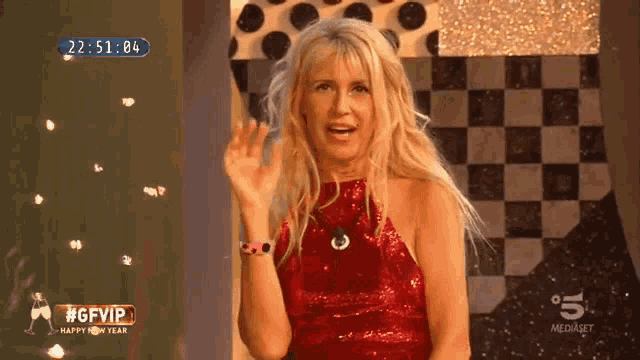 a woman in a red dress waves in front of a sign that says #gfvip happy new year