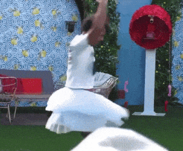 a man in a white dress is dancing in front of a red phone booth