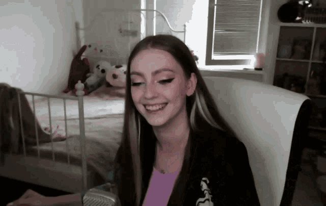 a girl with long hair is smiling in front of a microphone