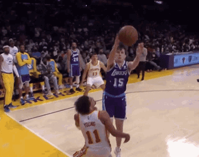 a basketball player wearing a lakers jersey is jumping for the ball