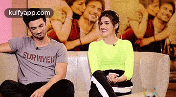 a man and a woman are sitting on a couch . the woman is wearing a neon green shirt .