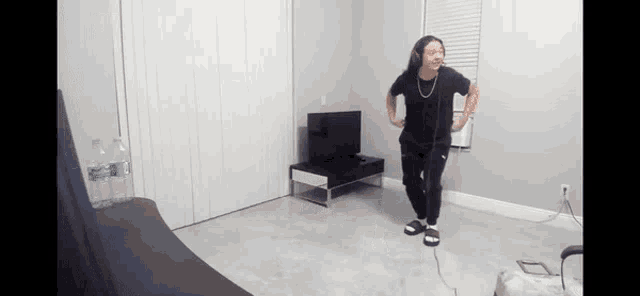 a woman is dancing in a living room in front of a television and a bottle of water .