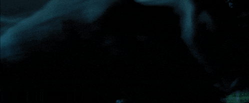 a group of people are standing in a dark room looking at something