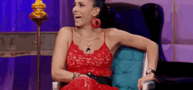 a woman in a red dress is sitting in a chair with her arms crossed .