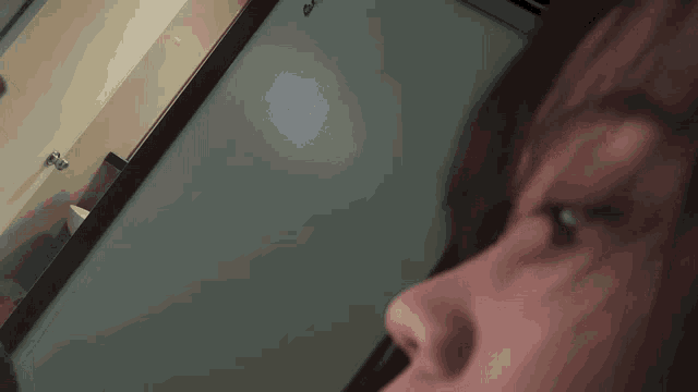 a close up of a person 's face with a gray wall in the background