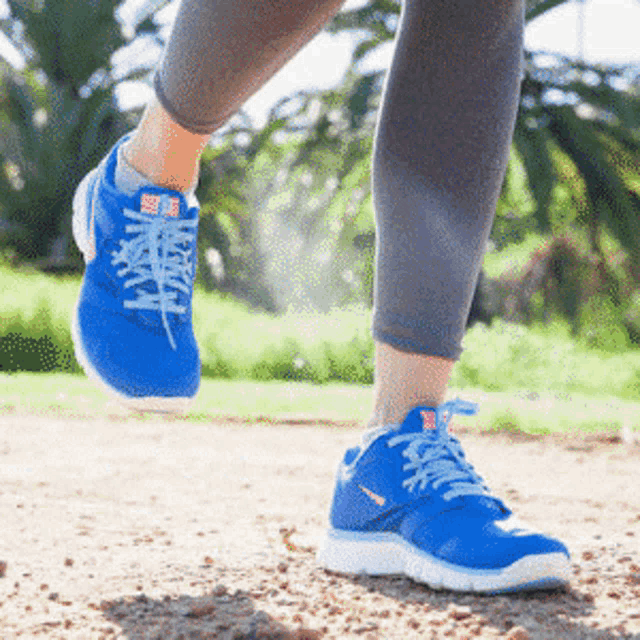 a person wearing blue nike shoes is walking on a dirt road