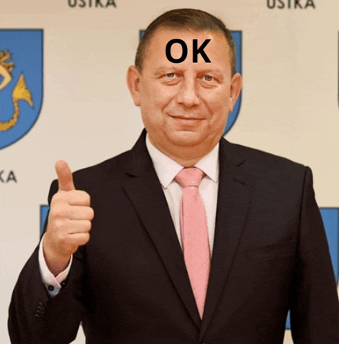 a man in a suit and tie with the word ok on his forehead