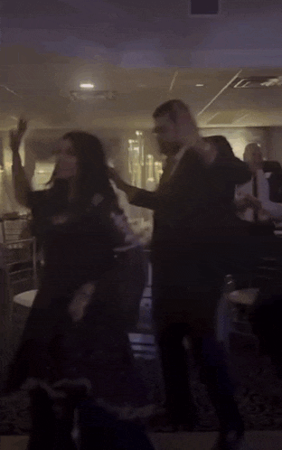a man in a suit and tie is dancing with a group of people