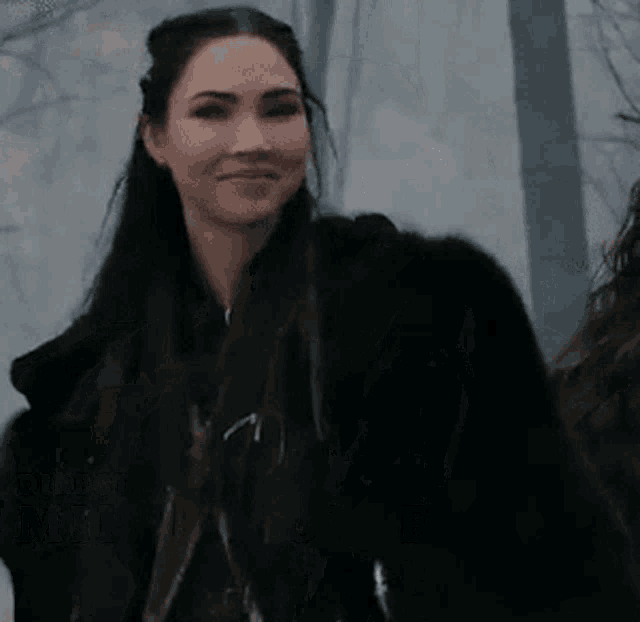 a woman in a fur coat is smiling with the name milan konjevic on the bottom right