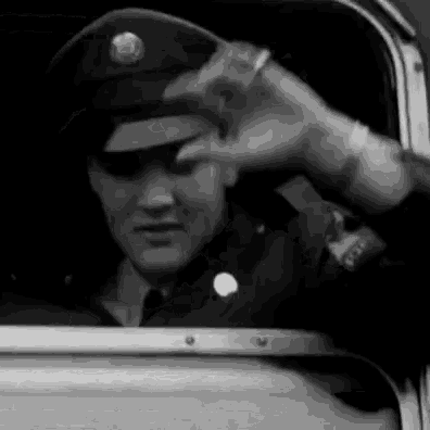 a man in a military uniform is sitting in a car and waving .