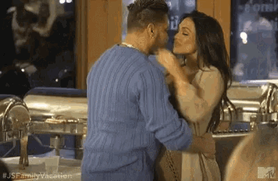 a man and a woman are hugging and kissing in a kitchen .