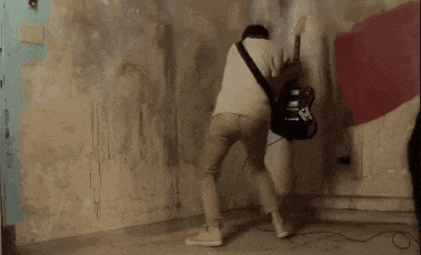 a man playing a guitar in a room with graffiti on the walls