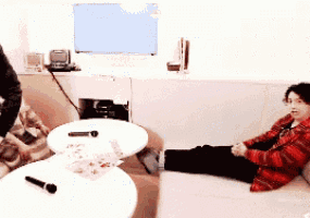 a man in a red plaid shirt is laying on a couch in a living room .