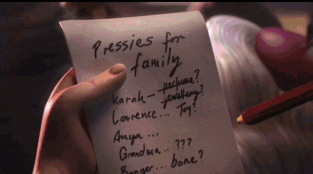 a person is holding a piece of paper that says pressies for family