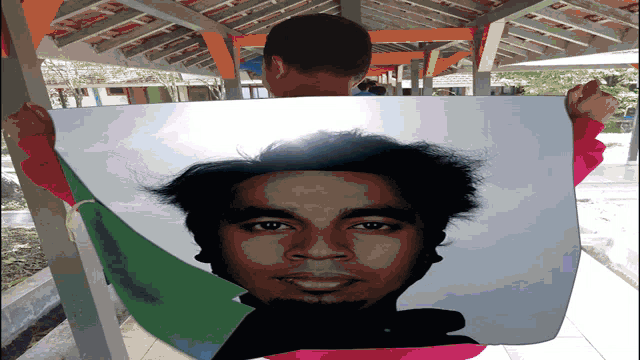 a man is holding a picture of a man 's face in front of his face