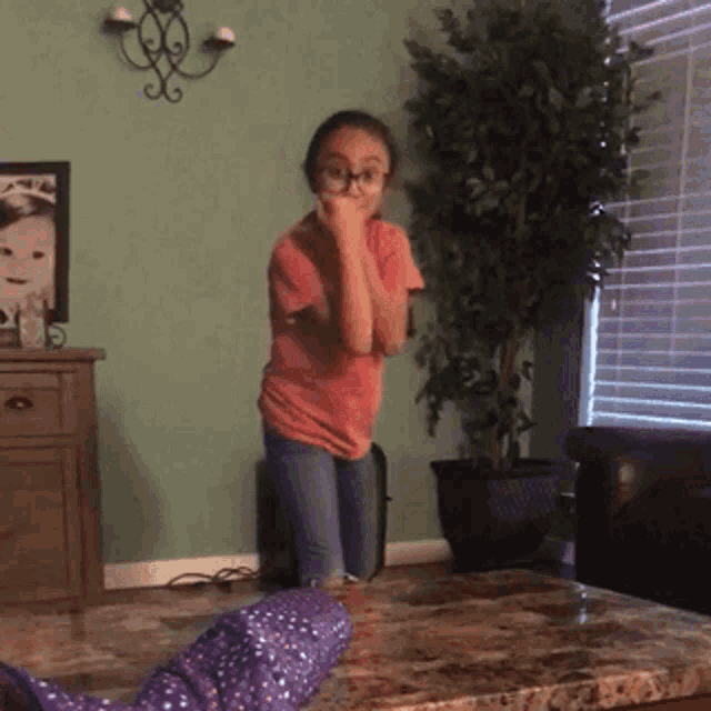 a little girl is dancing in a living room in front of a picture of a baby
