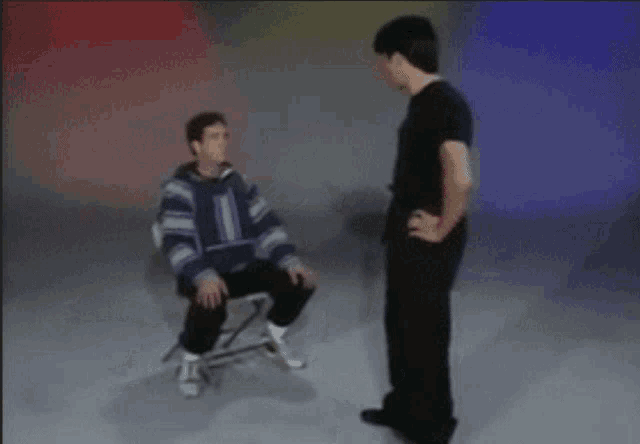 a man in a striped sweater is kicking another man in a chair